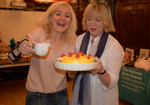 Sophie Thompson and Joanna David inspect a cake at the National Hospital for Neurology and Neurosurgery in Queen Square, Bloomsbury