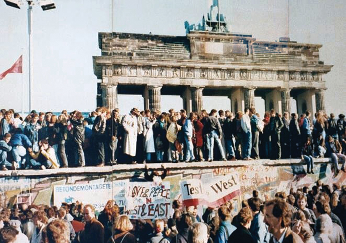 West and East Germans at Berlin Wall in front of the Brandenburg Gate in 1989 shortly before its fall_photo CC BY-SA 3.0 Deed